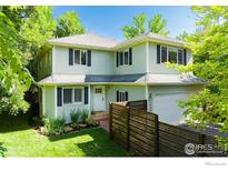 Charming two-story home featuring a well-manicured lawn, lush trees, and a two-car garage, perfect for Gathering living at 1409 Quince Ave, Boulder, CO 80304