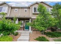 Inviting townhome exterior with stone accents, manicured landscaping, and a vibrant green door at 14700 E 104Th Ave, Commerce City, CO 80022