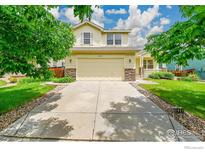 Inviting two-story home featuring a spacious driveway, attached garage, and manicured lawn at 1824 Ute Creek Dr, Longmont, CO 80504