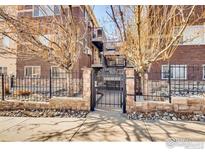 Brick apartment building featuring a secure gated entrance and mature trees adding to its curb appeal at 2345 N Clay St # 6, Denver, CO 80211