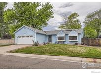 Charming light blue single-story home with a well-maintained front yard, attached garage, and beautiful landscaping at 7951 S Estes St, Littleton, CO 80128