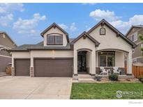 Charming stucco home with a three-car garage, covered porch, and well-manicured lawn at 11511 E 118Th Ave, Commerce City, CO 80640