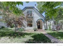Charming two-story home featuring a quaint balcony, arched entryway, and well-manicured lawn with mature trees at 1315 Gaylord St, Denver, CO 80206