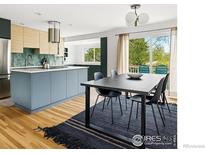 Bright kitchen and dining area features wood floors, blue island and cabinets, and backyard view at 1350 Lehigh St, Boulder, CO 80305