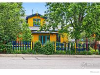 Charming yellow two-story home with blue trim and a blue and yellow picket fence at 2320 22Nd St, Boulder, CO 80304