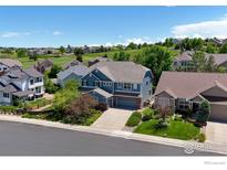 This aerial view shows a blue home with a well-manicured lawn and driveway at 23570 E Holly Hills Way, Parker, CO 80138