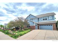Charming two-story home with blue siding, brick accents, and an attached two-car garage, plus a landscaped yard at 23570 E Holly Hills Way, Parker, CO 80138