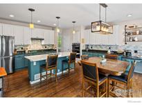 Bright kitchen boasts a center island with seating, stainless appliances, and an adjacent dining area at 23570 E Holly Hills Way, Parker, CO 80138