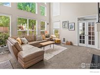 Bright living room with large windows, a comfortable sofa, and neutral decor at 23570 E Holly Hills Way, Parker, CO 80138