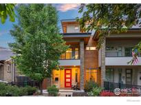 Striking modern home featuring wood and stone accents, a bright red front door, and manicured landscaping at 3845 N Raleigh St, Denver, CO 80212