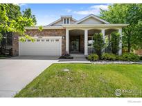 Charming home featuring a stone facade, covered porch with columns, and a well-maintained lawn at 4444 Fireweed Trl, Broomfield, CO 80023
