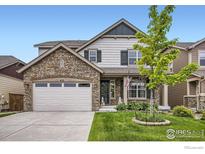 Charming home with a stone facade, two-car garage, and well-manicured lawn on a sunny day at 853 Jenny Ln, Berthoud, CO 80513