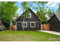Charming home with dark siding, white trim, green lawn, and trees in a peaceful, inviting setting at 133 Placer Ave, Longmont, CO 80504