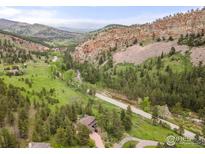 Stunning aerial view of the home nestled in a scenic mountain canyon near a river and road at 1946 Lefthand Canyon Dr, Boulder, CO 80302