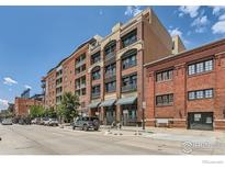 Street view of multi-story brick condo building with street parking at 2245 Blake St # D, Denver, CO 80205