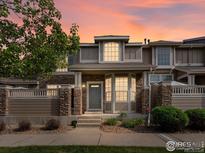 Charming townhome featuring stone accents, large windows, covered entry, and a well-maintained front yard at 4795 Raven Run, Broomfield, CO 80023