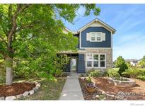 Charming two-story home with stone and blue siding, landscaped yard, and walkway to front door at 633 Deerwood Dr, Longmont, CO 80504