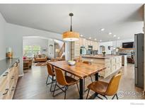 Open concept dining room featuring hardwood floors, modern table set, and views into the living area and kitchen at 682 Briar Dale Dr, Castle Pines, CO 80108