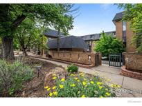 Inviting condo complex with brick accents, flowerbeds, mature trees, and manicured landscaping at 1065 University Ave # 121, Boulder, CO 80302