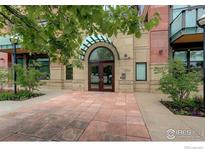 Elegant building entrance with arched doorway and manicured landscaping at 1077 Canyon Blvd # 211, Boulder, CO 80302