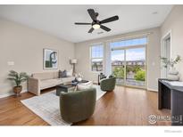 Bright living room featuring wood floors, contemporary furnishings, and a sliding door to a private balcony with mountain views at 13598 Via Varra # 404, Broomfield, CO 80020