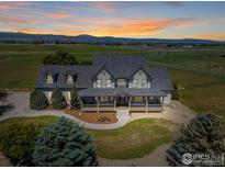 Stunning two-story home featuring a covered porch with breathtaking mountain views at sunset at 1625 Peak Ln, Erie, CO 80516