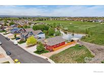 Charming, red two-story home with a fenced yard, next to a pond and open fields at 2767 Stallion Way, Mead, CO 80542