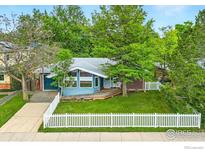 Charming single-story home with a blue facade, deck, white picket fence, and mature landscaping at 50 S 31St St, Boulder, CO 80305