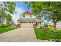 Charming two-story home featuring a two-car garage, well-manicured lawn, and inviting curb appeal at 5023 Goshawk Ct, Brighton, CO 80601