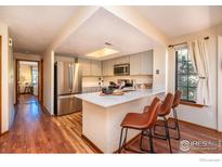 Bright kitchen with stainless steel appliances, light gray cabinets, breakfast bar, and hardwood floors at 5950 Gunbarrel Ave # E, Boulder, CO 80301