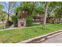 Two-story home with a covered porch, lush landscaping, and mature trees surrounding the property at 820 Kimbark St # D, Longmont, CO 80501