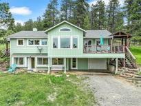 Charming two-story home with a deck, garage, and well-maintained lawn surrounded by lush trees at 849 Mountain Meadows Rd, Boulder, CO 80302