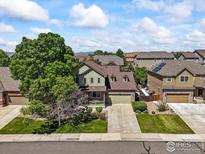 Charming two-story home with lush front lawn, mature trees, and inviting front porch at 13445 Kearney St, Thornton, CO 80602