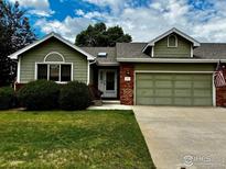 Charming single-Gathering home with a two-car garage, landscaped lawn, and combination brick-green siding at 1515 Tulip Ct, Longmont, CO 80501