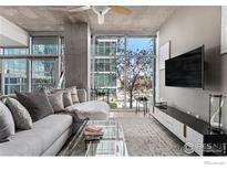 Bright living room features floor to ceiling windows and a comfortable gray sectional sofa at 1700 Bassett St # 903, Denver, CO 80202