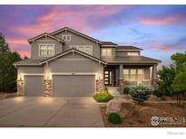 Charming two-story home with a three-car garage and manicured front yard at sunset at 3075 Blue Mountain Dr, Broomfield, CO 80023