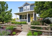Charming two-story home with a welcoming front porch, white railings and a beautifully landscaped yard and vibrant yellow door at 518 Hoyt Ln, Lafayette, CO 80026
