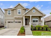 Charming home featuring a covered front porch, manicured lawn, and an attached two-car garage at 767 Cabot Dr, Erie, CO 80516