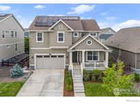 Charming two-story home with solar panels, a covered front porch, and a well-manicured lawn at 767 Cabot Dr, Erie, CO 80516