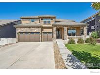 Charming two-story home with a three-car garage, stone accents, and a well-manicured lawn at 775 Longs Peak Dr, Erie, CO 80516