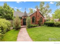 Charming brick home featuring a well-manicured lawn, stone pathway, mature landscaping, and unique architectural details at 1226 Dexter St, Denver, CO 80220