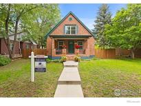 Charming brick home with a well-maintained lawn and inviting front porch and manicured garden at 205 E Colorado Ave, Berthoud, CO 80513