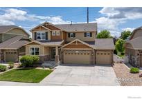 Inviting two-story home with a three-car garage, lush lawn, and charming stone accents, perfect for Gathering living at 2211 Winding Dr, Longmont, CO 80504