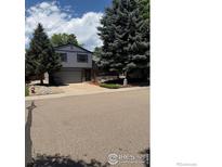 Two-story home with gray siding, mature trees, and a well-maintained front yard at 2449 Linden St, Longmont, CO 80501