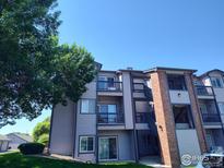 Three-story apartment building with balconies and a brick staircase is shaded by trees at 50 19Th Ave, Longmont, CO 80501