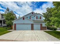 Two-story home with a three-car garage, light blue siding, and red shutters at 678 Mcclure Ct, Erie, CO 80516