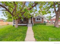 Charming single-story home with a covered front porch and mature trees in a well-manicured lawn at 11385 Downing Dr, Northglenn, CO 80233
