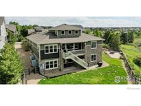 A multi-level home featuring a stone facade, a wooden staircase leading to a second-story deck, and lush green surroundings at 24725 E Dry Creek Pl, Aurora, CO 80016