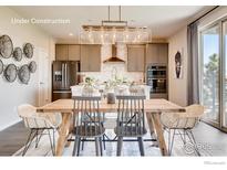 Open-concept dining area featuring a wooden table, modern chandelier, and seamless transition to a kitchen space at 2739 Crystal Springs Ln, Longmont, CO 80503