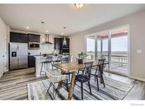 Open-concept kitchen features an island with seating, stainless steel appliances, and a dining area with access to a patio at 2739 Crystal Springs Ln, Longmont, CO 80503